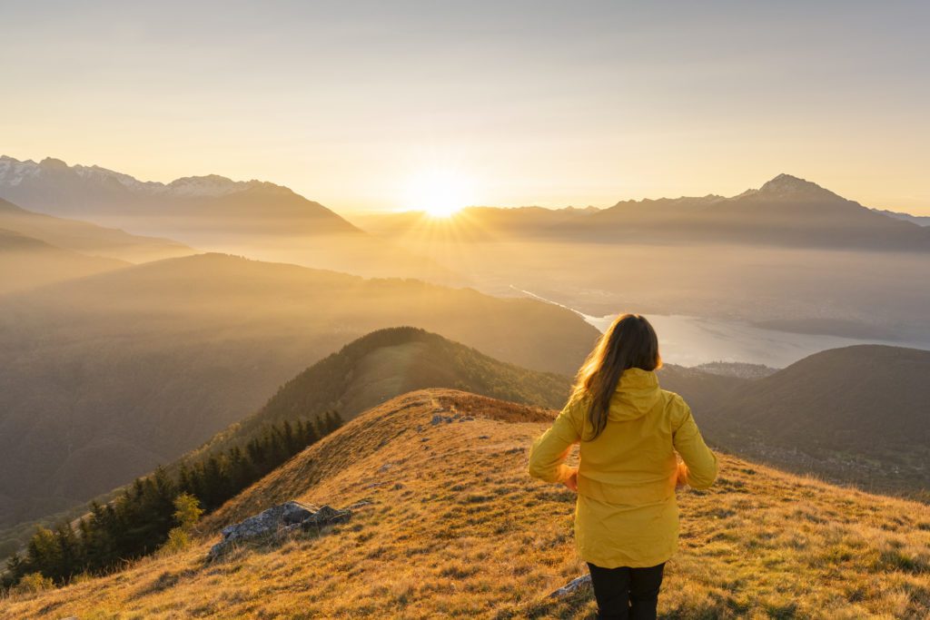 A woman gazing at lake and mountains from high up